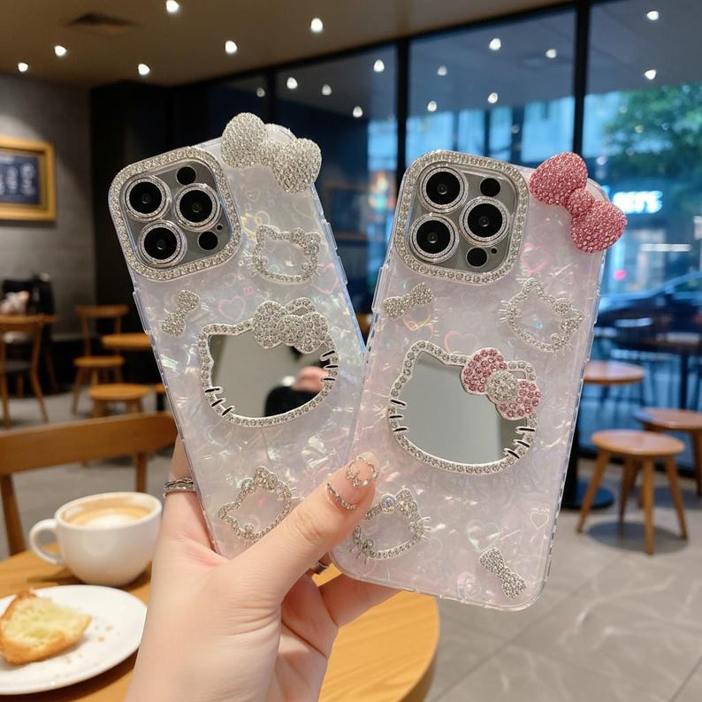 Puede incluir: Dos fundas transparentes para tel&eacute;fono con acabado nacarado, adornadas con brillantes pedrer&iacute;a. Cada funda presenta un dise&ntilde;o de Hello Kitty, que incluye un lazo y un espejo. Un lazo es plateado, el otro es rosa.