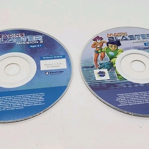 May include: Two computer CD-ROMs for educational games. One is "Reading Blaster Mission 2" with a cartoon astronaut. The other is "Math Blaster Mission 2" with cartoon characters. Both discs are blue and white.