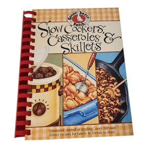 May include: A spiral-bound cookbook titled Slow Cookers, Casseroles & Skillets by Gooseberry Patch. The cover features illustrations of a slow cooker, a blue baking dish with food, and a black skillet, with the text Simmered, stirred or sizzling.