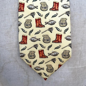 May include: A yellow necktie with a repeating pattern of red boots, fish, fishing nets, and tackle boxes. The tie has a pointed end and is made of a smooth fabric.