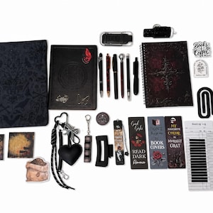 May include: A collection of stationery and accessories including a black patterned pouch, a black journal with butterfly stickers, five pens, a spiral notebook, various stickers, a heart keychain, a hair clip, four bookmarks, and a reading log sheet.