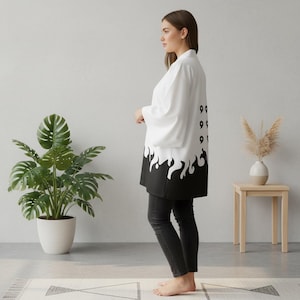 May include: White kimono-style robe with black flame design at the hem and the number "99" printed on the back. The robe is worn over black pants. The robe has wide sleeves and a relaxed fit.