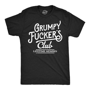 May include: Black t-shirt with the text "Grumpy Fucker's Club" in white, stylized lettering. Below the club name is the text "Lifetime Member". The shirt has a crew neck and short sleeves.