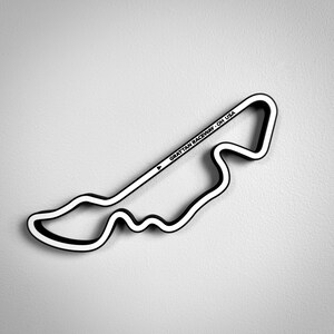 May include: A black and white wall-mounted sculpture depicting the Grattan Raceway track layout. The piece features a continuous outline with a white centre and black border, including the text GRATTAN RACEWAY - OH USA printed along one straight section.
