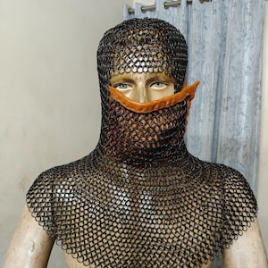 May include: A black chainmail coif featuring a dark metal ring construction that covers the head and shoulders, paired with a tan leather face mask that covers the nose and mouth area, secured with a visible metal ring on the side.