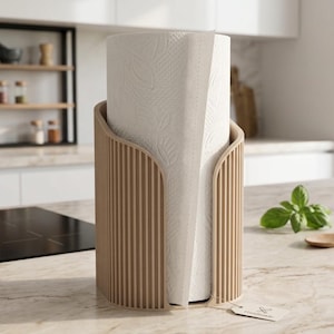 May include: A cylindrical paper towel holder with a light wood-toned, vertically ribbed exterior. The holder contains a roll of white paper towels featuring a subtle embossed leaf pattern. A small rectangular tag is attached to the base.
