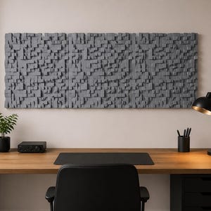 May include: A large rectangular wall art piece composed of numerous small, gray, protruding wooden blocks of varying depths and sizes, creating a textured, three-dimensional surface mounted horizontally above a wooden desk.