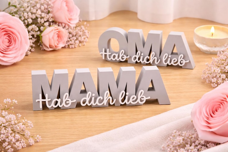 Zwei personalisierte 3D-gedruckte Geschenkschilder mit der Aufschrift „MAMA“ und „OMA“ sowie dem Schriftzug „Hab dich lieb“. Die grauen Deko-Schilder sind auf einem Holztisch mit rosa Rosen dekoriert – eine emotionale und stilvolle Geschenkidee zum Muttertag oder Geburtstag.