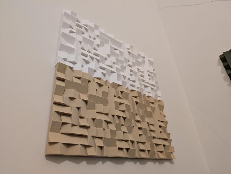 May include: A square wall-mounted acoustic panel featuring a three-dimensional geometric design. The top half is composed of white blocks, while the bottom half consists of tan blocks, creating a textured surface with varying depths.