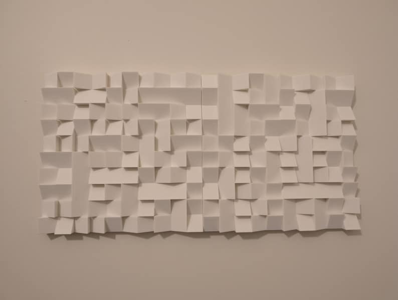 May include: A rectangular white wall art piece composed of numerous folded paper segments creating a three-dimensional geometric relief pattern with varying depths and shadows across the entire surface of the structure.