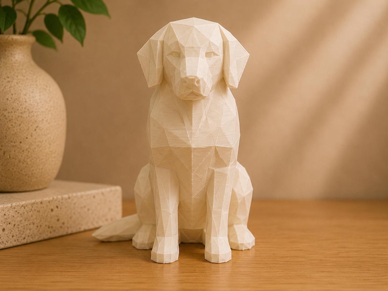 May include: A cream-colored, low-poly geometric sculpture of a sitting dog. The figure is constructed from numerous flat, triangular facets that form the shape of the canine's head, ears, body, and legs, creating a sharp, angular appearance.