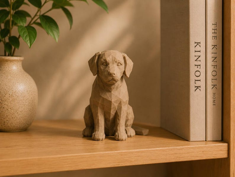May include: A light brown, geometric-style dog figurine with a faceted, angular surface texture. The sculpture depicts a seated dog with floppy ears, a defined snout, and a neutral expression, crafted with a matte finish and solid construction.