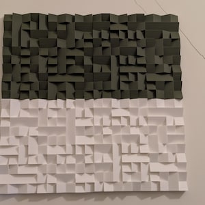 May include: A square wall art piece featuring a three-dimensional geometric design made of folded paper. The top half consists of dark olive green paper segments, while the bottom half is composed of white paper segments, creating a high-contrast look.