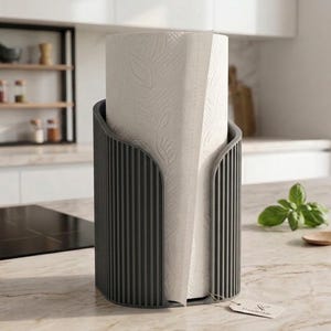 May include: A dark gray, cylindrical paper towel holder with a vertical ribbed texture. The holder contains a roll of white paper towels featuring a subtle embossed leaf pattern. A small, rectangular paper tag is attached to the base.