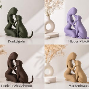 May include: A set of four monochromatic sculptures depicting a person kneeling and embracing a dog. The figures are available in dark green, lilac, dark chocolate brown, and desert tan. Each sculpture is labeled with its color name in German.