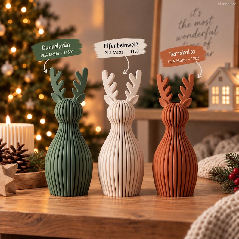 May include: Three reindeer figurines with vertical ribbed textures, colored dark green, off-white, and terracotta. Each features antlers and a rounded body. Labels indicate Dunkelgr&uuml;n 11501, Elfenbeinwei&szlig; 11100, and Terrakotta 1203, all PLA Matte.