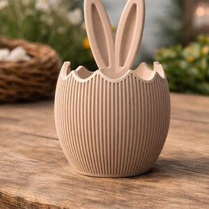 May include: A set of three ceramic mugs with a speckled, matte finish. The mugs are in cream, light grey, and dark grey. Each mug has a simple, minimalist design, ideal for coffee or tea.