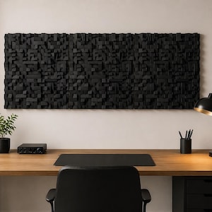 Puede incluir: Un panel de pared negro, texturizado y geométrico cuelga sobre un escritorio de madera. El escritorio cuenta con una alfombrilla negra, una pequeña planta en maceta, una lámpara negra y un portalápices. Una silla negra está delante.
