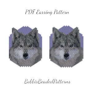 May include: A pair of beaded wolf head earrings, each with a gray and white design, set against a lavender background. The text "PDF Earring Pattern" and "BobbisBeadedPatterns" are displayed.
