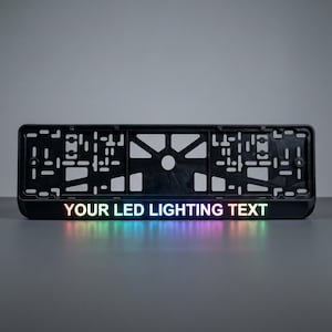 Pode incluir: Moldura preta para placa de carro com o texto "YOUR LED LIGHTING TEXT" iluminado em cores do arco-íris. A moldura tem formato retangular com vários recortes e um orifício central de montagem.