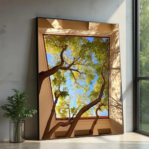 May include: A framed art print featuring a view of tree branches reaching towards a blue sky. The artwork is set within a rectangular opening, framed by a beige structure with a red-tiled roof. The image is displayed indoors, leaning against a wall.