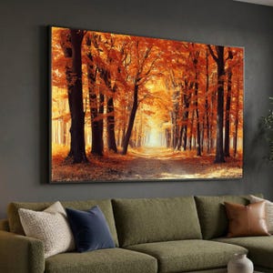 Può includere: Stampa su tela incorniciata raffigurante una vivace scena di foresta autunnale. L'opera d'arte mostra un sentiero che conduce in lontananza, incorniciato da alti alberi con fogliame arancione e giallo. La stampa è montata su una parete scura sopra un divano verde.