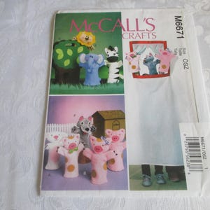 May include: A McCall's Crafts sewing pattern envelope, model M6671, featuring illustrations of various animal hand puppets including a lion, elephant, zebra, wolf, and pigs. The white envelope displays the brand name, model number, and a barcode.
