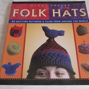 May include: A book titled "Folk Hats" with 32 knitting patterns and tales from around the world. The cover features a woman wearing a colorful knitted hat with a bird on top.