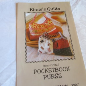 May include: A tan paper with the text "Kimie's Quilts" and "Pocketbook Purse." The image shows two quilted purses, one orange and white, the other white, red, and black. Item # LJK126 is also visible.