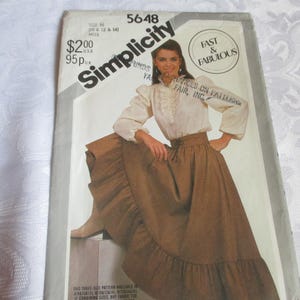 May include: Simplicity sewing pattern 5648 featuring a woman in a long brown skirt and a cream-colored blouse. The pattern includes the text "Fast & Fabulous" and the price $2.00.