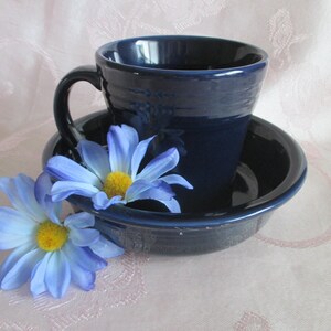 May include: A blue ceramic mug and saucer set with a blue and white daisy on the side.