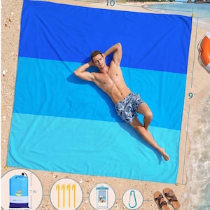 May include: A large, rectangular beach blanket in shades of blue, measuring 10 feet by 9 feet. The blanket is divided into three horizontal sections of varying blue hues. Included are stakes, a waterproof phone case, a carabiner, and a carrying bag (7 inches by 5 inches).