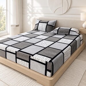 May include: A bed set featuring a fitted sheet and two pillowcases with a geometric grid pattern in shades of gray, black, and white. The fabric displays alternating textures of solid blocks, ribbed lines, and zebra-like stripes.