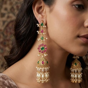 Può includere: Orecchini pendenti dorati con pietre preziose verdi e rosse e perle bianche pendenti. Gli orecchini presentano un design floreale e un fondo a forma di campana, mostrando uno stile elegante e ornato.