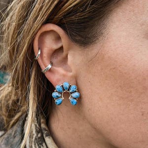 May include: A white ceramic mug with a black handle and the text "But First, Coffee" in a black, handwritten-style font. The mug is on a white surface.