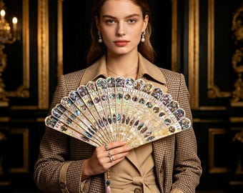 May include: A hand fan featuring an intricate arrangement of iridescent mother-of-pearl segments and inlaid shell accents. The fan displays a semi-circular structure with a light-colored frame and a delicate, matching tassel hanging from the base handle.