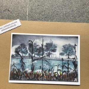 Könnte beinhalten: Ein rechteckiges Aquarellbild, das eine Landschaft mit einem blauen See, dunklen, silhouettierten Schilfrohren im Vordergrund und Bäumen unter einem bewölkten grauen Himmel zeigt. Das Kunstwerk trägt unten rechts eine Signatur mit den Initialen JK.