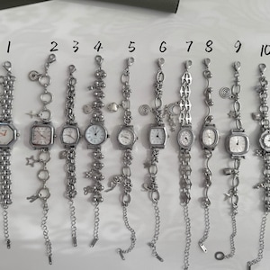 以下が含まれることがあります： 10個のシルバーカラーのチャームブレスレットのコレクション。それぞれに時計が付いています。時計の文字盤の形は、八角形、正方形、円形など様々です。各ブレスレットには、さまざまなチャームとチェーンのデザインがあり、さまざまな装飾要素が施されています。