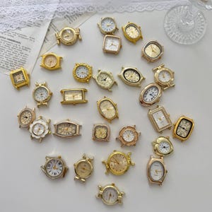 Pode incluir: Uma coleção de mostradores de relógio em metal dourado com diversas formas, incluindo redondas, quadradas, ovais e retangulares. Cada peça apresenta um mostrador com ponteiros e marcadores de hora, concebida como componente para joalharia.