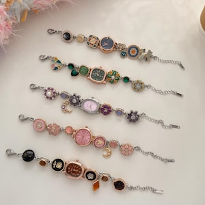 Puede incluir: Cinco pulseras de reloj decorativas con varios adornos coloridos. Las esferas de los relojes son de diferentes formas y colores, incluyendo rosa, verde y azul. Las pulseras tienen cadenas plateadas y dijes decorativos.