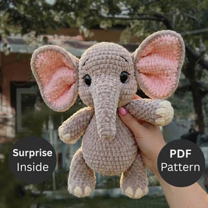 Puede incluir: Un juguete de elefante de peluche tejido a ganchillo con hilo marrón claro, grandes orejas internas de color rosa suave, ojos negros oscuros y detalles en color crema en los pies. La imagen incluye textos circulares negros que dicen Surprise Inside y PDF Pattern.