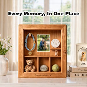 May include: A wooden pet memorial display case with the text "Every Memory, In One Place." It features a photo, paw print, collar, teddy bear, stone, and tennis ball. The text "Forever in our hearts" is at the bottom.