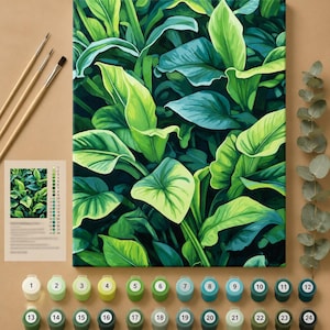 Op de afbeelding: Een schilderen-op-nummer set met een canvas voorzien van een tropisch bladpatroon in tinten limoen, smaragd en donkergroen. De set bevat drie penselen, een genummerde kleurengids en vierentwintig kleine potjes met genummerde acrylverf.