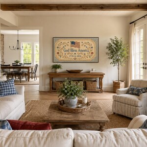 Pu&ograve; includere: Una targa da parete rettangolare con sfondo beige e bordo a scacchi blu. Il testo 'God Bless America' &egrave; centrato in blu, affiancato da tralci floreali e una piccola bandiera americana. Le date '1776' e '2026' appaiono sotto il testo.