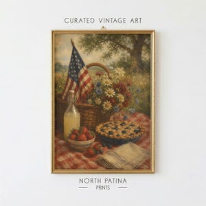 May include: A framed vintage-style art print titled CURATED VINTAGE ART and NORTH PATINA PRINTS featuring a picnic scene with a woven basket, an American flag, a glass bottle of lemonade, a bowl of strawberries, a blueberry pie, and a cloth napkin.
