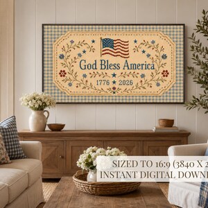 Pu&ograve; includere: Un quadro rettangolare con sfondo beige e bordo a quadretti blu e bianchi. Il testo God Bless America &egrave; centrato sopra gli anni 1776 e 2026, affiancato da tralci floreali, stelle e una piccola bandiera americana.