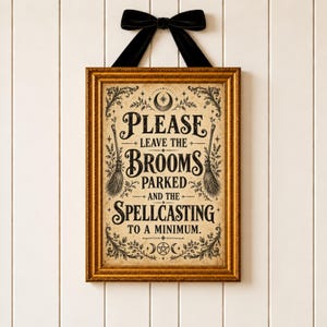 May include: A rectangular wall sign in a gold frame with a black velvet bow at the top. The sign features a cream-colored background with black text that reads: Please leave the brooms parked and the spellcasting to a minimum, with broom illustrations.