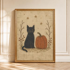 May include: A framed needlepoint art piece on a beige burlap background featuring a black cat sitting next to an orange pumpkin. The design includes embroidered bare branches with red berries on both sides and small gold stars scattered above.