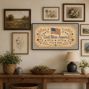 Pu&ograve; includere: Una targa da parete rettangolare con sfondo beige e bordo a quadretti vichy blu e bianchi. Il testo recita God Bless America con gli anni 1776 e 2026. Include una grafica della bandiera americana e motivi decorativi a tralci floreali.