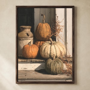 May include: A framed wall art print depicting a still life scene with several pumpkins of varying sizes and colors, including orange, white, and muted green, arranged on wooden steps next to a weathered ceramic jug and dried foliage.